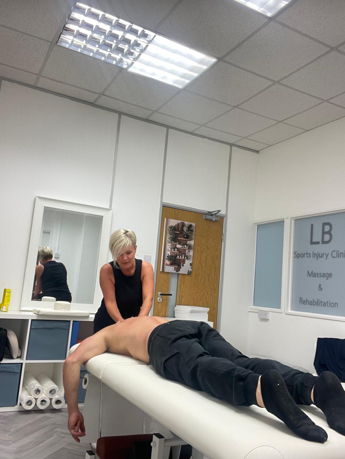 Lisa applying sports massage treatment to a client's back